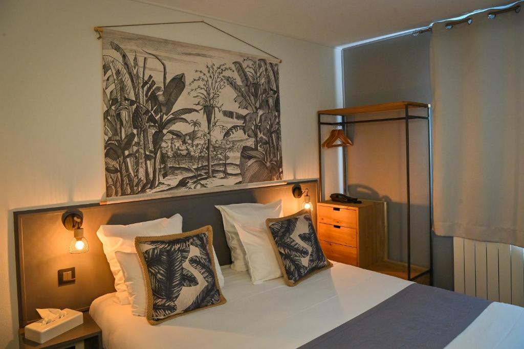 - une chambre avec un lit avec des oreillers et un tableau dans l'établissement Hôtel Le Pavillon de Saint-Lô - anciennement Lunotel, à Saint Lo