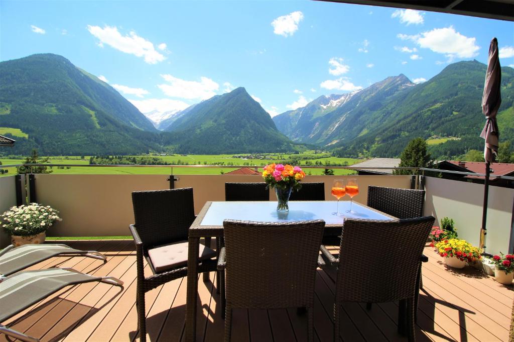 a patio with a table and chairs and mountains at Appartements Cilli in Neukirchen am Großvenediger