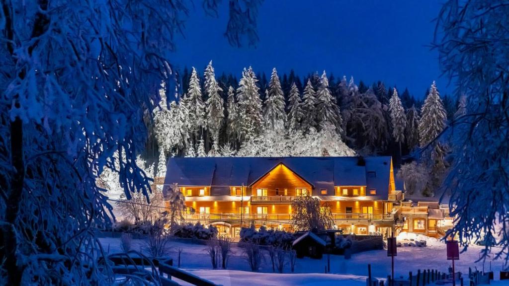 a house in the snow at night at Hotel Restaurant Mont Champ du Feu in Belmont