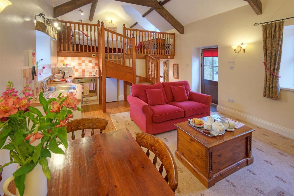 sala de estar con mesa y sofá rojo en Rose Cottages, en Alnwick