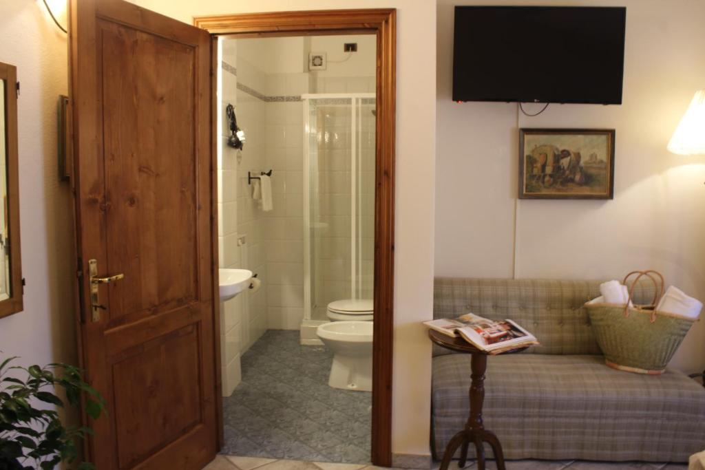 a bathroom with a toilet and a television on the wall at Boutique Hotel Fox's Inn in San Giustino Valdarno