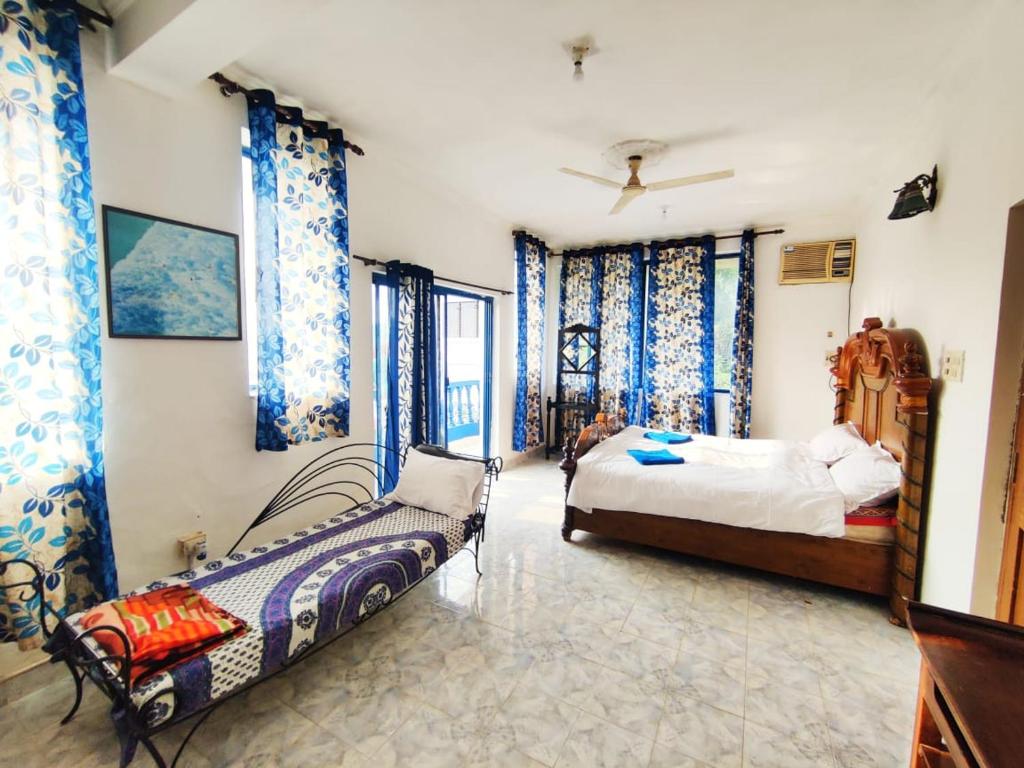 1 dormitorio con 2 camas y cortinas azules en Amazing Hilltop 4 BHK Villa with Private Pool near Candolim en Candolim