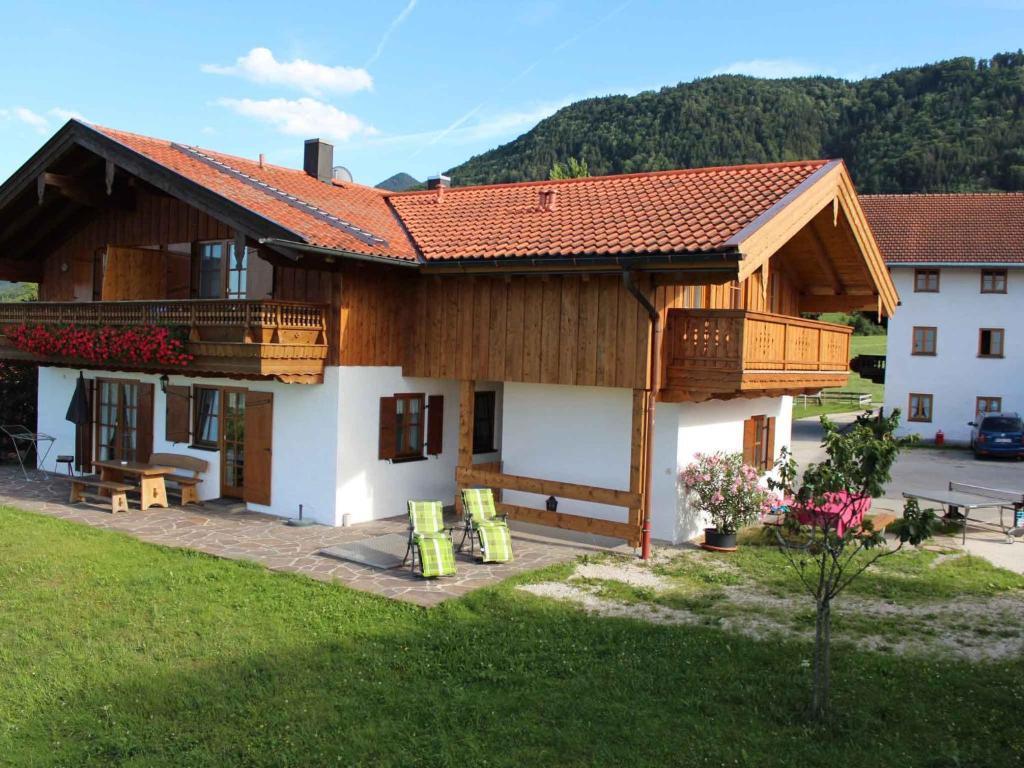 a house with a wooden roof and a yard at Schneiderhof Urlaub auf dem Bauernhof in Bernau am Chiemsee