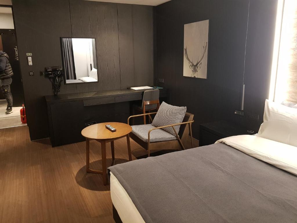um quarto com uma cama, uma mesa e uma cadeira em Anseong City Hotel em Anseong