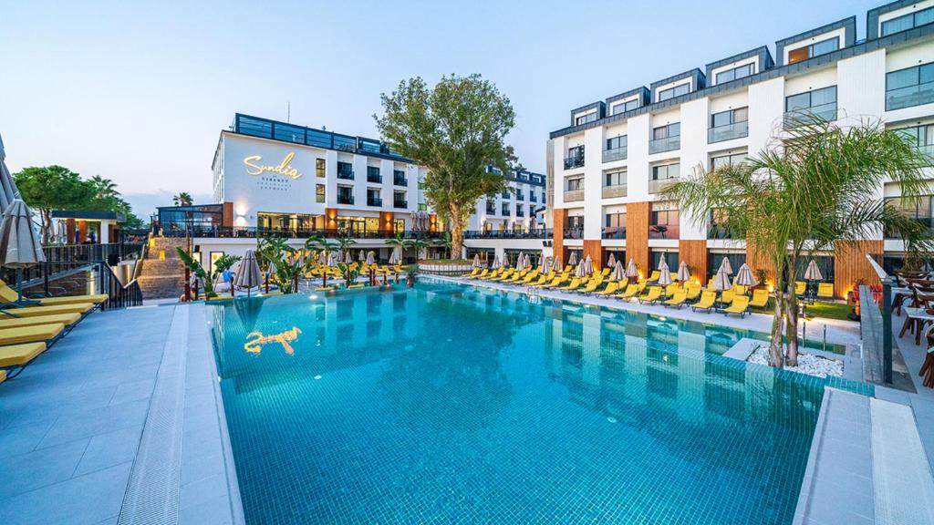 a large swimming pool with yellow chairs and a building at Sundia Exclusive By Liberty Fethiye in Fethiye