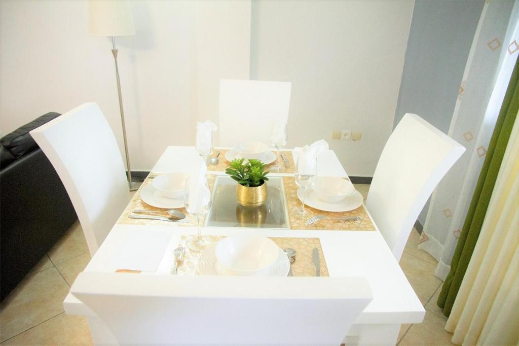 une table blanche avec des plats blancs et une plante sur elle dans l'établissement ABT Apartments Bonapriso-7Mins From Airport, à Douala