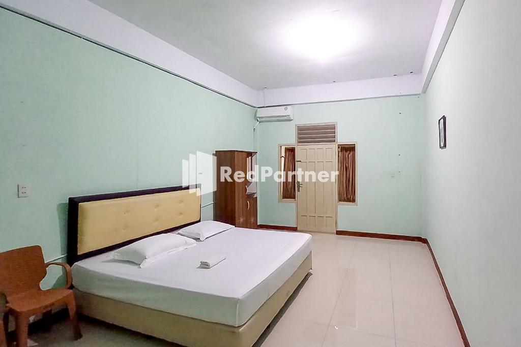 um quarto com uma cama e uma cadeira em Sutomo Indah Homestay Syariah Mitra RedDoorz em Padangsidimpuan