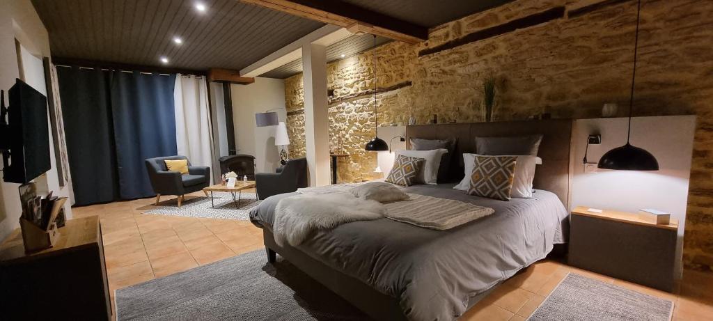 a bedroom with a large bed with a stone wall at Le Clos de la Tour in Sainte-Nathalène