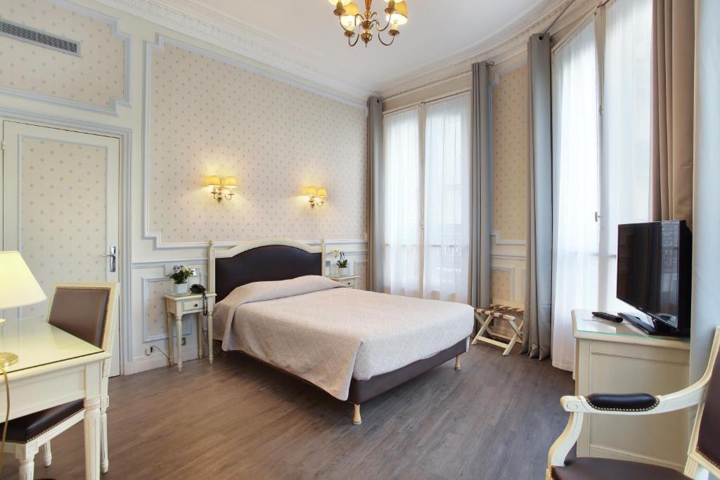 a bedroom with a bed and a desk and a tv at HOTEL DU PRINTEMPS in Paris