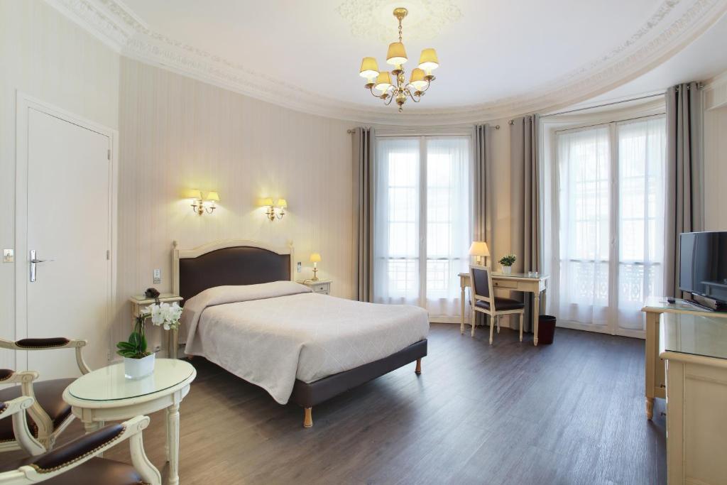 a bedroom with a bed and a tv and a couch at HOTEL DU PRINTEMPS in Paris