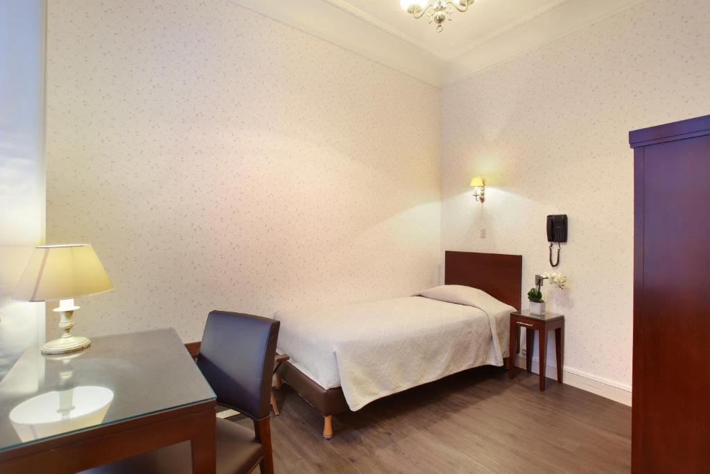 a bedroom with a bed and a table and a desk at HOTEL DU PRINTEMPS in Paris