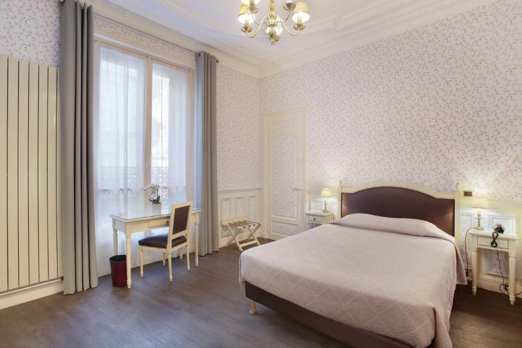 a bedroom with a bed and a table and a desk at HOTEL DU PRINTEMPS in Paris