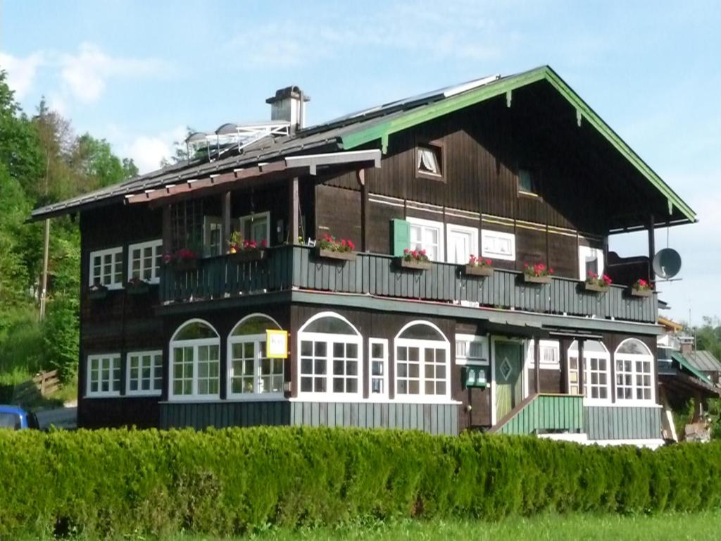 Cette maison en bois dispose de fenêtres blanches et d'un balcon. dans l'établissement Meistereders Ferienwohnung, à Schönau am Königssee