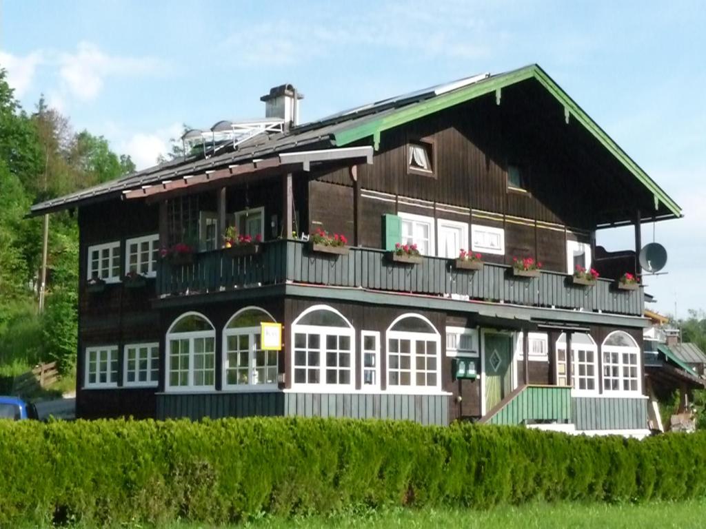 ein Holzhaus mit weißen Fenstern und einem Balkon in der Unterkunft Meistereders Ferienwohnung in Schönau am Königssee