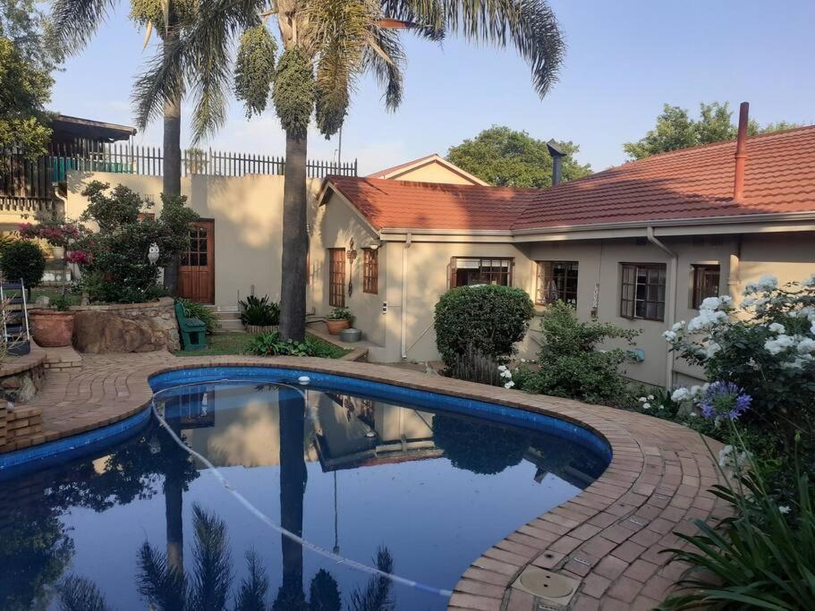 a house with a swimming pool in front of a house at Stunning BnB in Gorgeous Garden Setting in Germiston