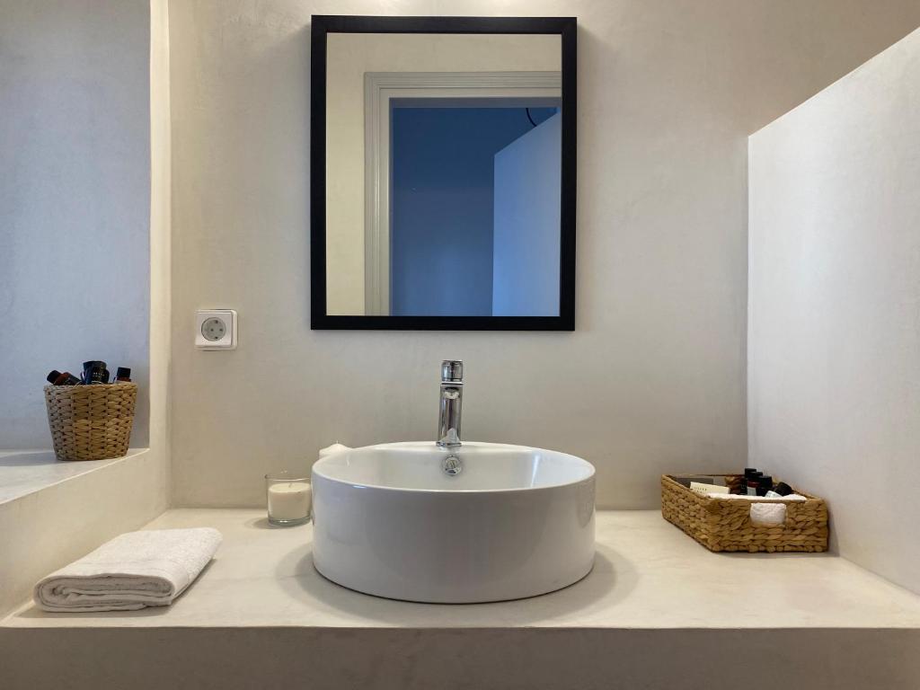 bagno con lavandino bianco e specchio di Arco Bianco Suites ad Akrotírion