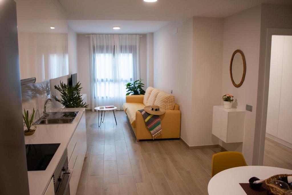 a living room with a yellow couch and a kitchen at Gloriamar Las Canteras in Las Palmas de Gran Canaria
