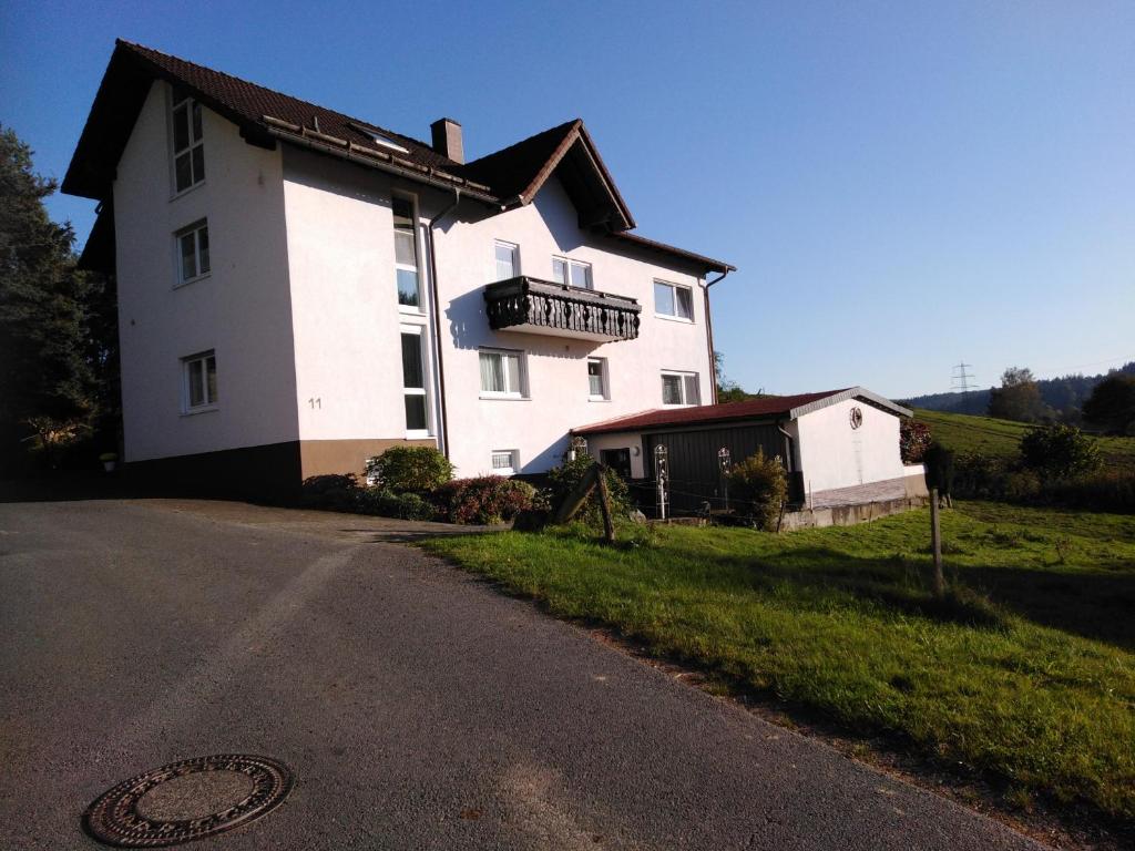 Casa blanca con balcón al lado de una carretera en Ferienwohnung Am Lindenrain, en Mossautal