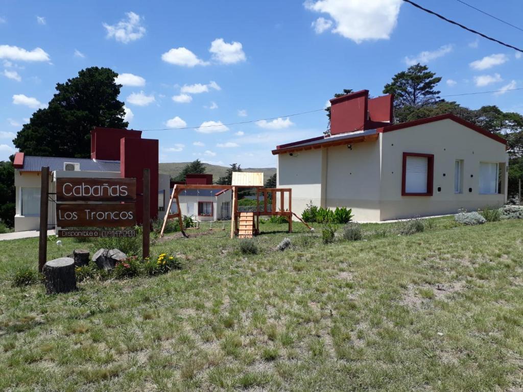 a house with a sign in front of it at Cabañas Los Troncos in Sierra de la Ventana