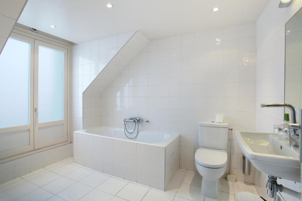 a white bathroom with a toilet and a sink at HOTEL DU PRINTEMPS in Paris