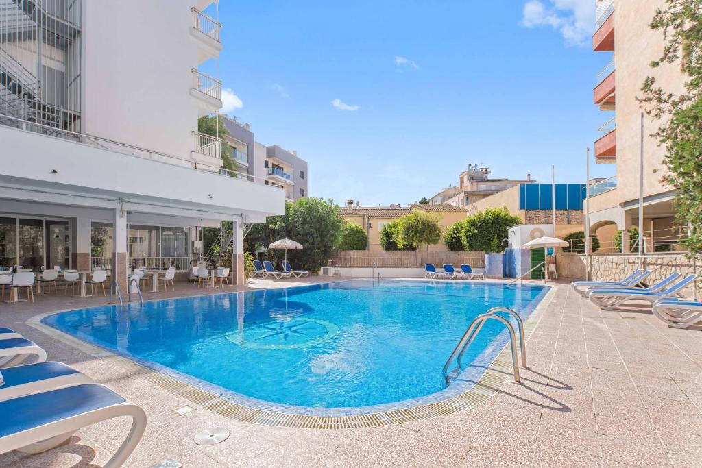 une grande piscine avec des chaises et un bâtiment dans l'établissement BLUESEA Piscis - Adults Only, à Port d'Alcúdia