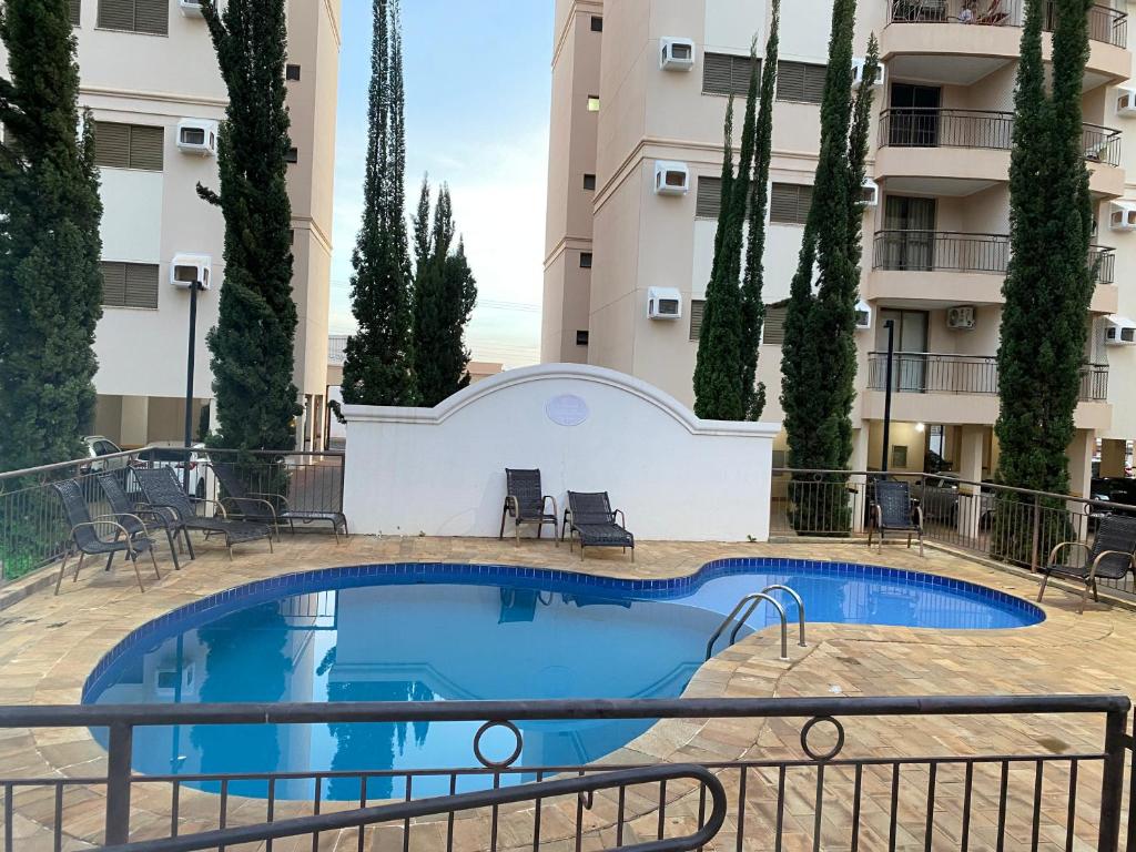 a swimming pool in front of a building at Apartamento Villagio in Olímpia