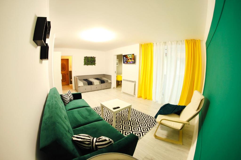 a living room with a green couch and yellow curtains at Studio F13 in Topliţa