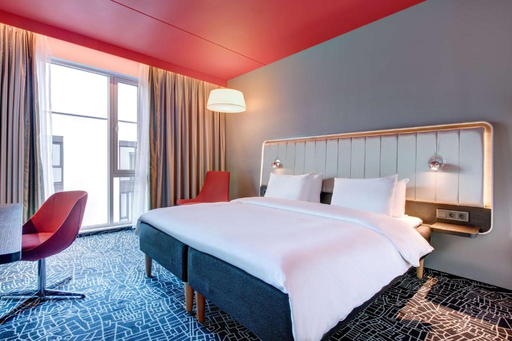 a hotel room with a large bed and red chairs at Radisson Blu Hotel Oslo Alna in Oslo