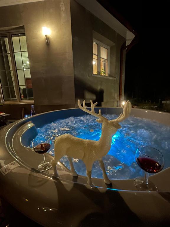 a statue of a deer in a tub with wine glasses at Apartamenty Paszkówka in Pietrzykowice