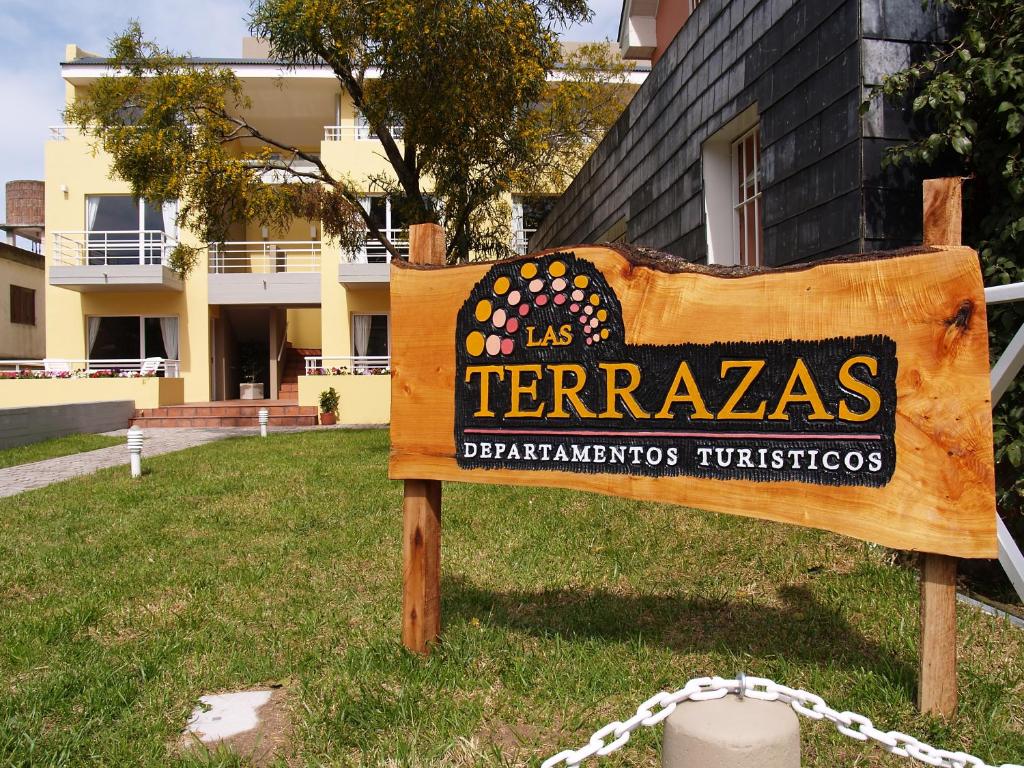 a sign in the grass in front of a building at Las Terrazas Departamentos Turisticos in Villa Gesell