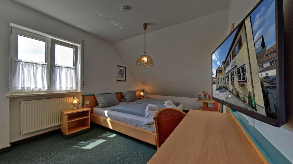 a bedroom with a bed and a tv and a table at Hotel Gasthof Lachner in Stetten
