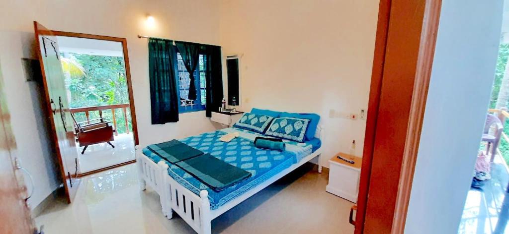 a bedroom with a bed with blue sheets and a window at BLUE SOPHY Residency in Varkala