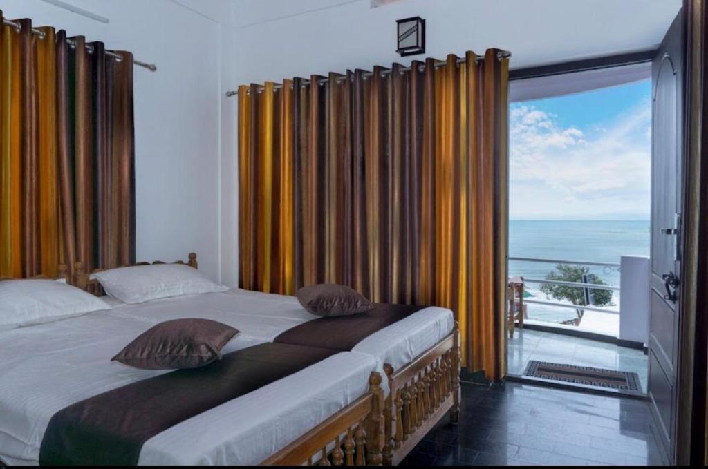 a bedroom with a bed and a large window at Sand castle varkala in Varkala