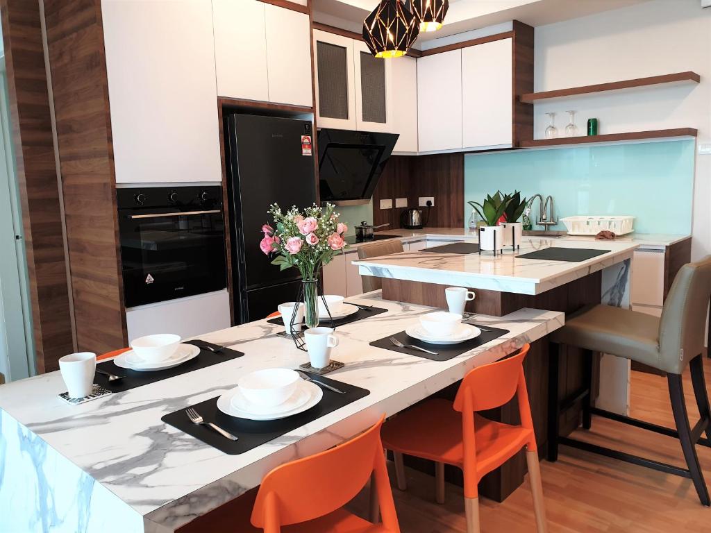 a kitchen with a large kitchen island with orange chairs at Best Moments Suite in Kuantan
