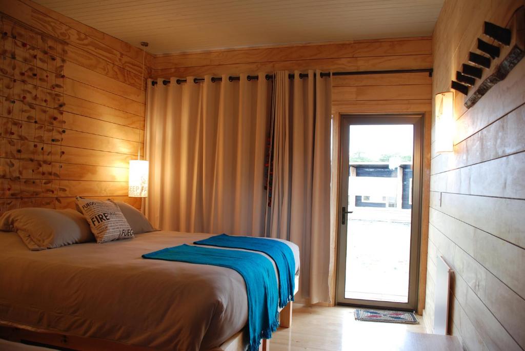 a bedroom with a bed and a sliding glass door at Rumbo Sur Hotel in Villa O'Higgins