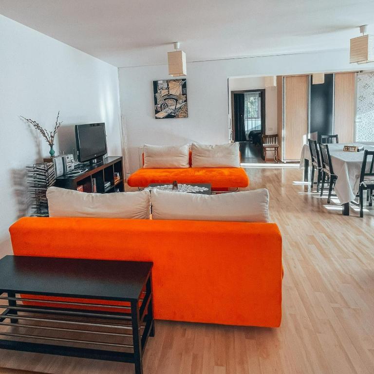 two orange beds in a room with a living room at Sebiana in Buşteni