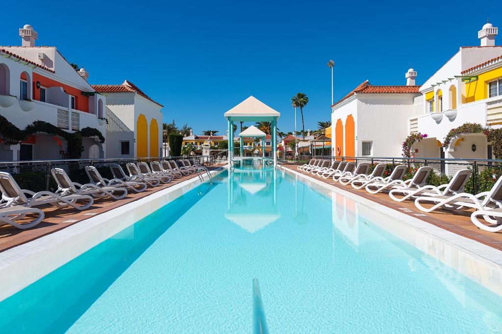 a swimming pool with chaise lounges and chairs at Bungalows Cordial Green Golf in Maspalomas