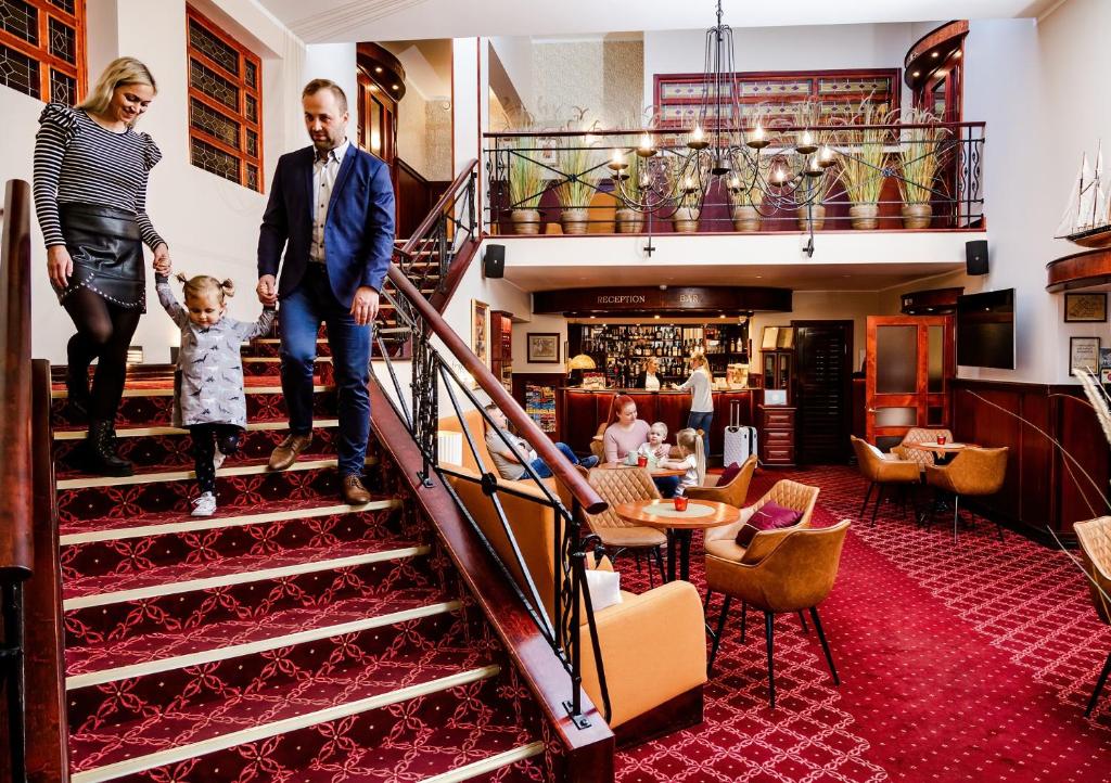 a man and a woman and a child walking down the stairs at Hotel Legend in Pärnu