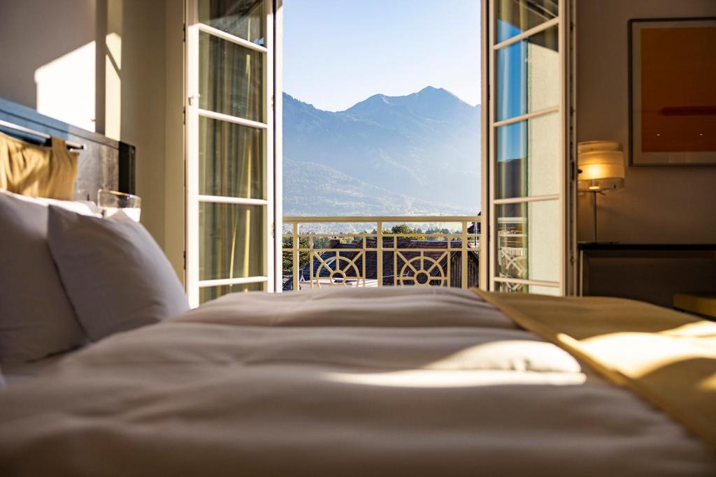 a bed in a bedroom with a view of a mountain at Sorell Hotel Tamina in Bad Ragaz