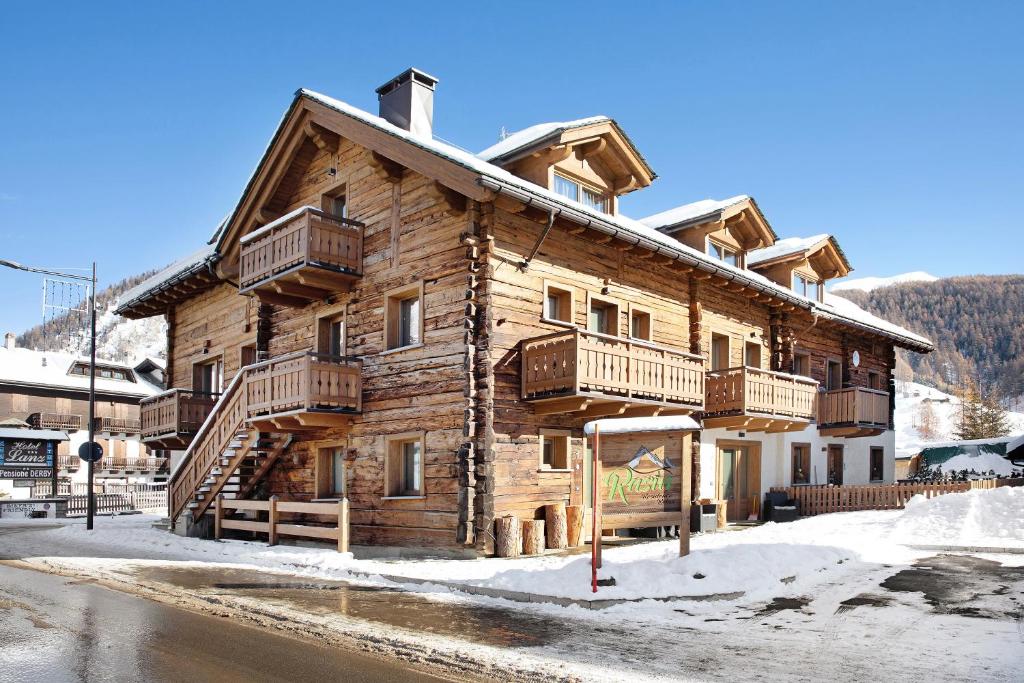 a log cabin with snow in front of it at Rasia Residence Relax Wood in Livigno