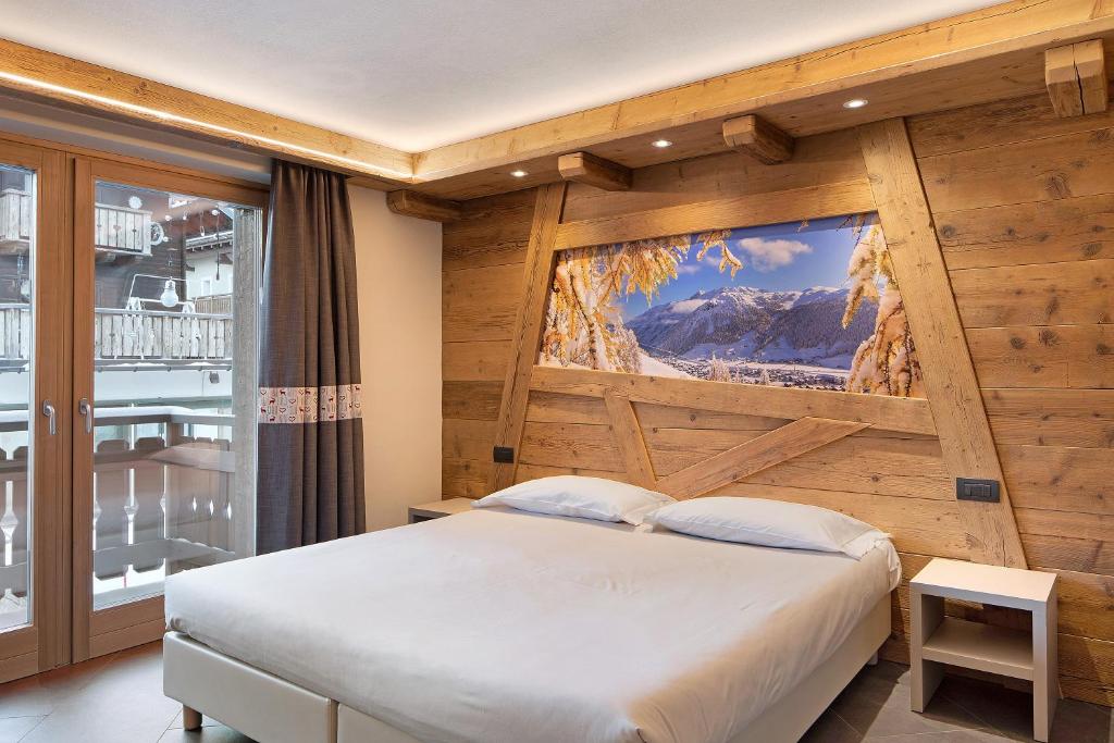 a bedroom with a bed and a wall with a tv at Rasia Residence Relax Winter in Livigno