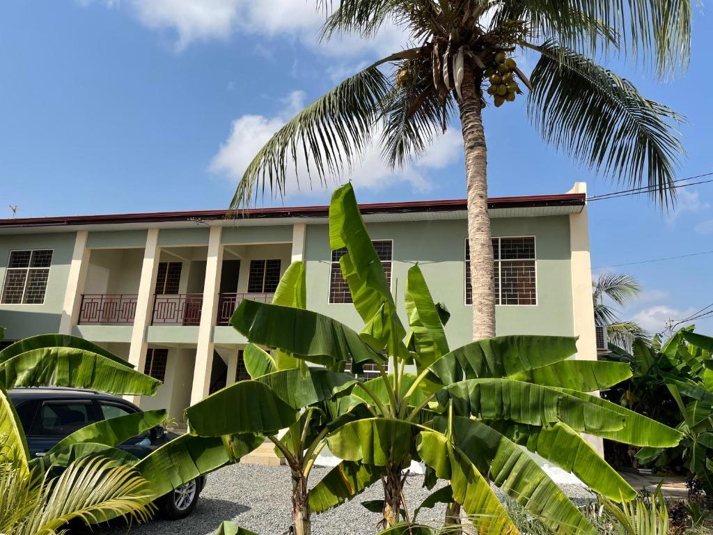 un edificio con una palmera delante de él en Connect Africa Apartments en Accra