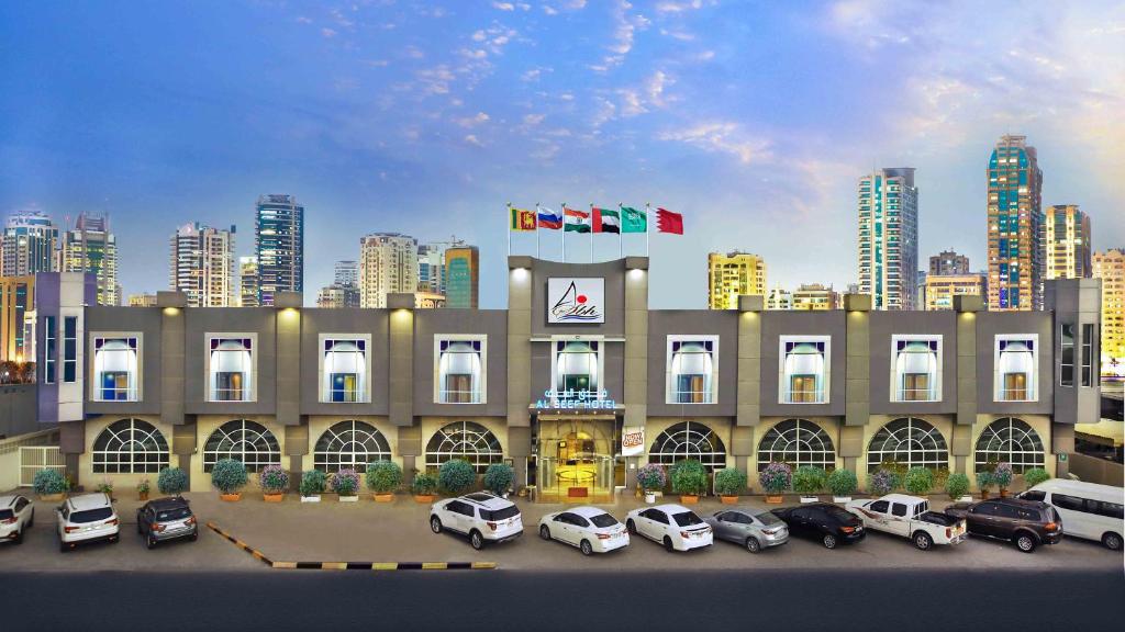 un gran edificio con coches estacionados en un estacionamiento en Al Seef Hotel, en Sharjah