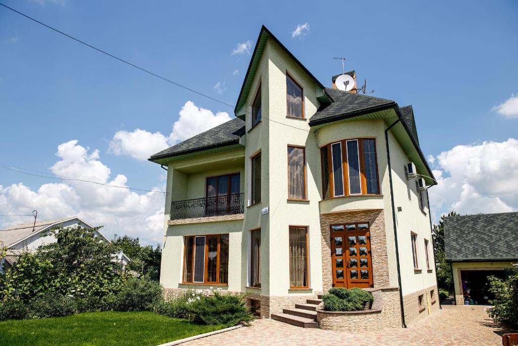 una casa bianca con un orologio sopra di Sweet Home Hostel a Černivci