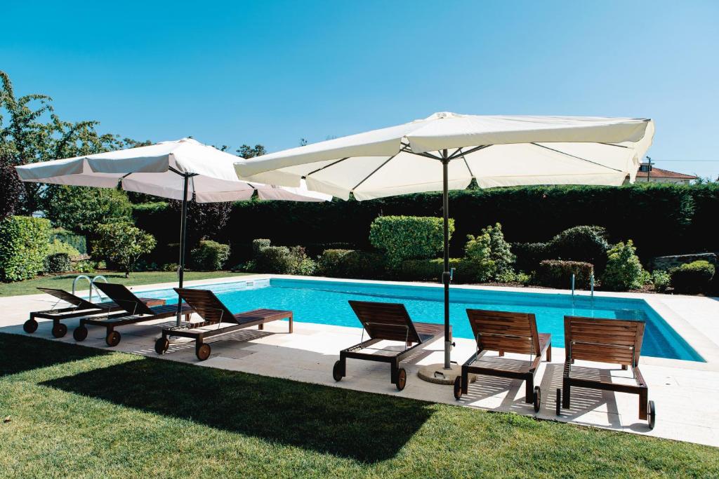 a group of chairs and umbrellas next to a pool at Feel Discovery Casa Da Capela Douro Valley Armamar in Armamar
