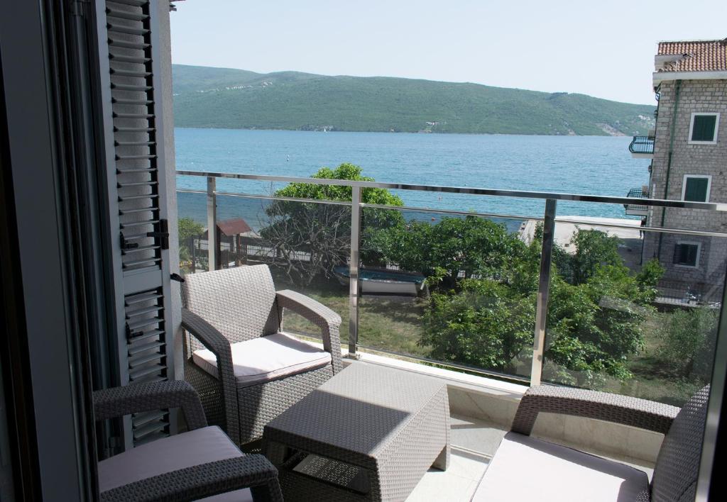 balkon z krzesłami i widokiem na wodę w obiekcie Apartments Admiral w mieście Herceg Novi