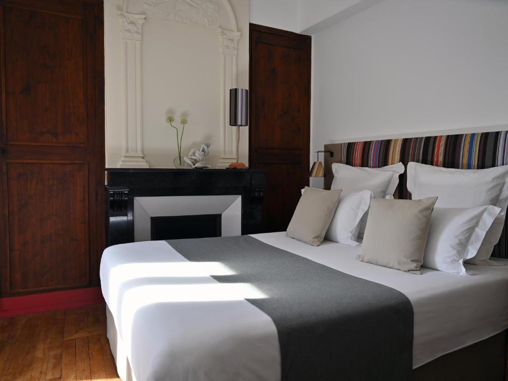 a bedroom with a large white bed and a fireplace at L'Hostalet in Argelès-sur-Mer