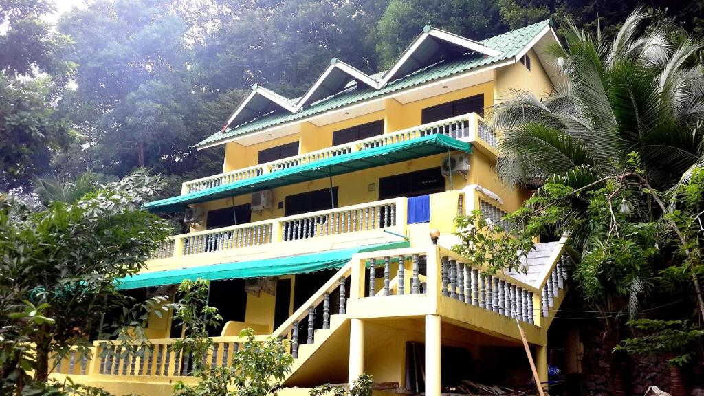 a yellow building with a balcony and trees at Island Lodge in Ko Chang