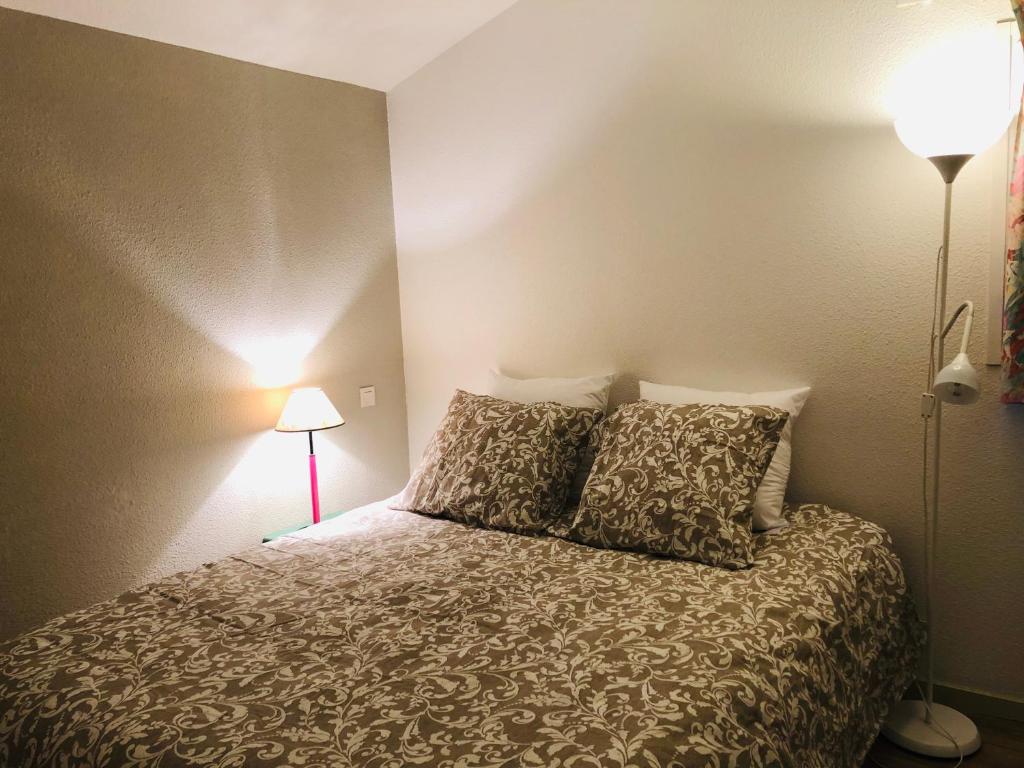 1 dormitorio con 1 cama con 2 almohadas y 2 lámparas en Lacanau Ocean : Maison de vacances dans la Pinede, en Lacanau