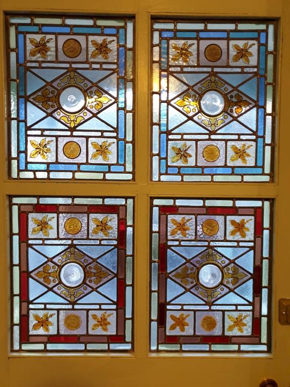 a trio of stained glass windows on a wall at Peggy Hill Cottage in Ambleside